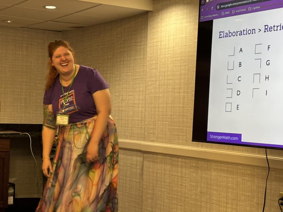 Shelby is bent over laughing while presenting at a conference