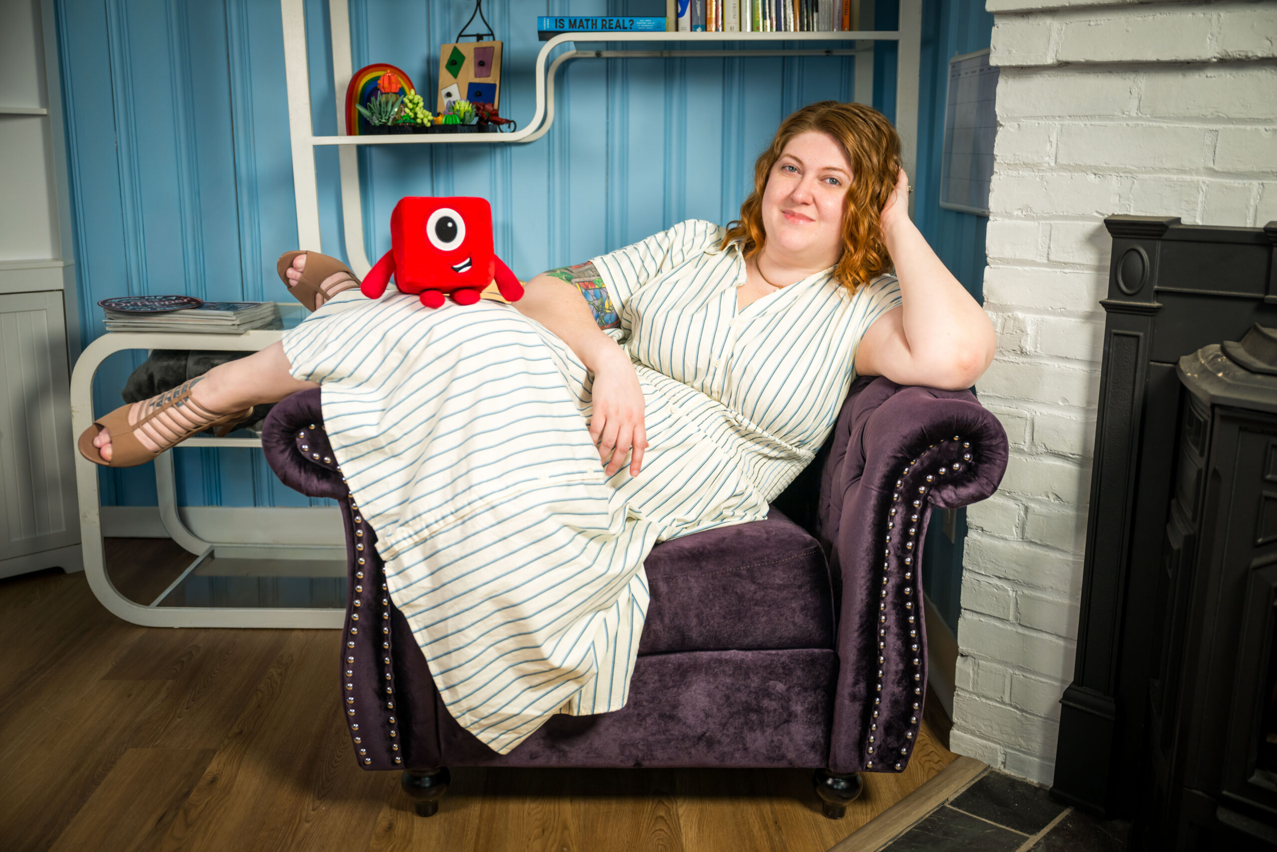 Shelby in a purple chair with a Numberblocks plush on her knee